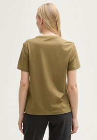 T-shirt en coton vert olive, à manches courtes et col rond, avec une coupe droite et une texture douce. La vue de dos montre un design simple.