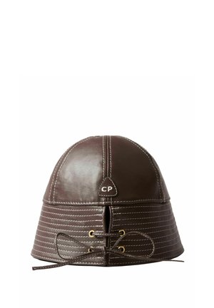 Cappello in pelle marrone con cima rotonda, cuciture orizzontali e un dettaglio di lacci frontali. Presenta un piccolo etichetta con il logo "CP". Finitura testurizzata.