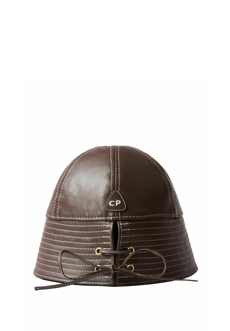 Cappello in pelle marrone con cima rotonda, cuciture orizzontali e un dettaglio di lacci frontali. Presenta un piccolo etichetta con il logo "CP". Finitura testurizzata.