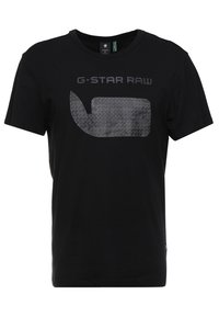 Camiseta negra de algodón con cuello redondo y mangas cortas. Presenta un logotipo gráfico gris en el frente con un patrón geométrico.