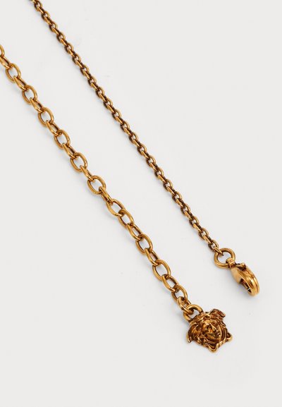 Catena in metallo tono oro con dettaglio a ciondolo raffigurante una testa di leone e moschettone. Superficie liscia e forma uniforme in tutto il design.