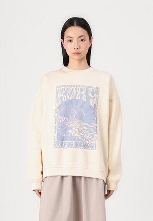 Crèmekleurige sweatshirt met een bedrukte blauwe surfontwerp en het woord "ROXY." Gemaakt van zachte stof, met een relaxte pasvorm en ribgebreide manchetten.