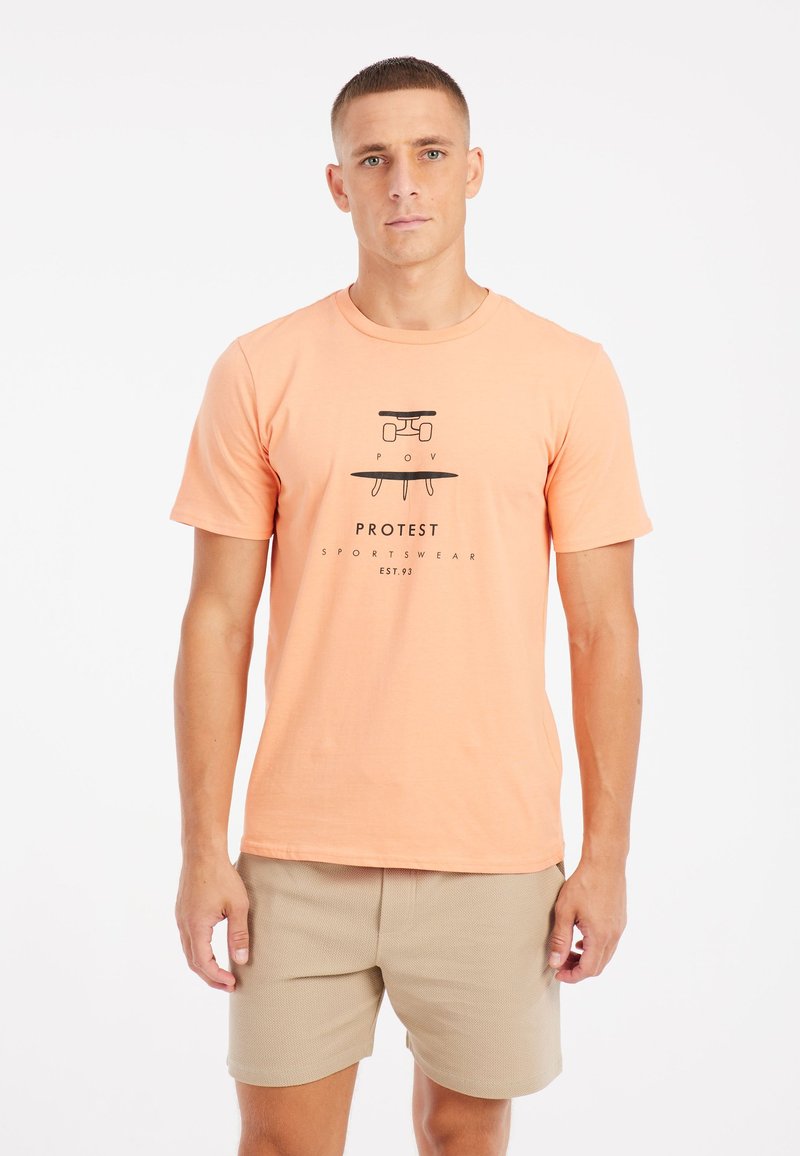Korte mouwen, perzikkleurig katoen t-shirt met een zwarte grafische print waarop de tekst "PROTEST SPORTSWEAR" staat en een eenvoudig ontwerp.