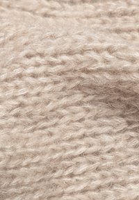 Beżowy dzianinowy materiał o miękkim, teksturowanym splocie, z różną grubością włókien i delikatnym połyskiem. Idealny do odzieży lub tekstyliów domowych.