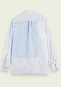 Camicia a quadri blu chiaro con diverse trame di tessuto, caratterizzata da righe e sezioni in tinta unita, maniche lunghe e polsini con bottoni. Dettaglio della yoke posteriore visibile.