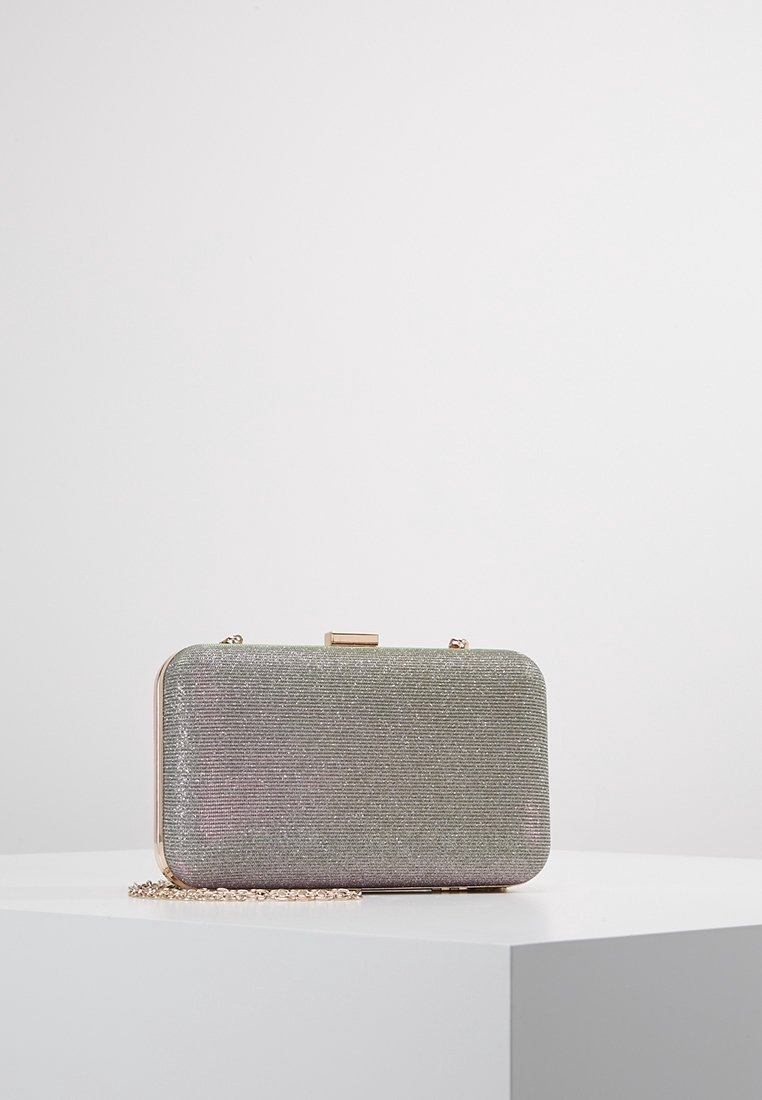 Petit sac pochette rectangulaire argenté pailleté avec cadre doré et bandoulière chaîne posé sur une surface blanche.