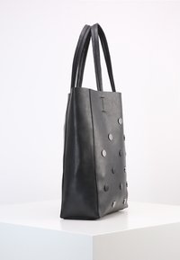 Černá kožená taška přes rameno s dvěma dlouhými uchy, velký obdélníkový tvar, texturovaný povrch a oblé stříbrné detaily na přední straně.