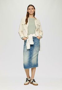 Jeansrock, hellblau, knielang, mit zwei Fronttaschen. Kombiniert mit einer weißen Jacke, gestreiftem grünen Shirt und mehrfarbigen Sneakern.