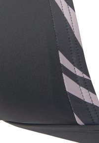 Zwart sporttop met ribbelstructuur, lichtroze en donkergrijze diagonale strepen en contrasterende stikseldetails.