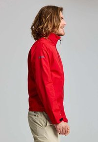 Rode waterdichte jas met hoge kraag, ritssluiting aan de voorkant, elastische manchetten en een getailleerde taille. Bevat logo op de linkermouw.