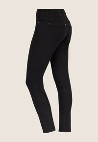 Vaqueros ajustados negros con cintura de tiro medio, bolsillos traseros y detalles de costura sutiles. Hechos de mezclilla con una textura suave.