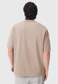 Κοντομάνικη μπλούζα με χαλαρή εφαρμογή, λείο ύφασμα και απλή στρογγυλή λαιμόκοψη, σε προβολή από πίσω.