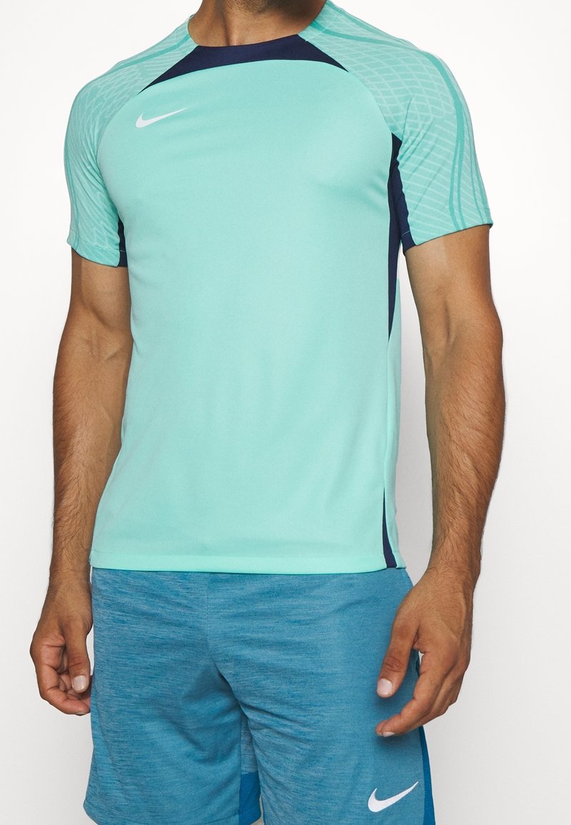 Camiseta atlética verde menta de manga corta con acentos azules. Fabricada con un tejido que absorbe la humedad. Logo de Nike en el pecho.