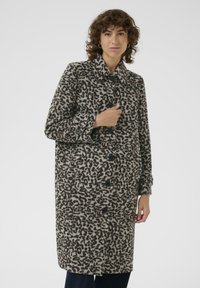 Manteau en laine à imprimé léopard avec des boutons noirs, col large et poches latérales ; design mi-long dans des tons neutres de beige et marron.