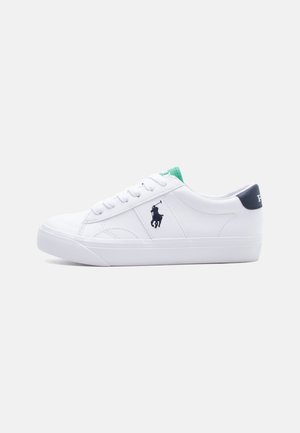 Biały niskoprofilowy sneaker z zapięciem na sznurowadła, czarne logo gracza polo po boku, zielona zakładka na języku i czarny akcent na pięcie.