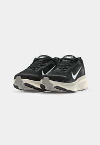 Schwarze Nike Laufschuhe mit Obermaterial aus Mesh, strukturierten Details, weißem Swoosh und beiger Zwischensohle. Verfügt über Schnürsenkel und eine strapazierfähige Gummisohle.