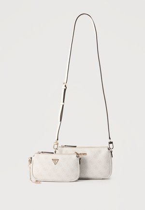 Kaksi pientä beigeä suunnittelijansiirtolaukkua, joissa kullansävytetty metalliosat ja säädettävä olkahihna, toinen ketjuyksityiskohdalla, vierekkäin valkoisella taustalla.