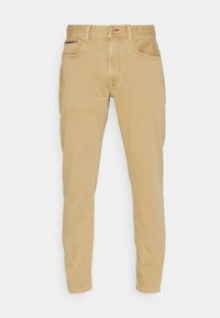 Khaki puuvillahousut slim fit -mallilla, viidellä taskulla ja nappikiinnityksellä. Etutaskussa on punainen yksityiskohta. Sileä rakenne.