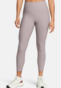 Leggings a vita alta in color lavanda tenue, con una trama a coste e una superficie liscia. Presentano una vestibilità slim e tasche laterali, abbinati a sneakers bianche.