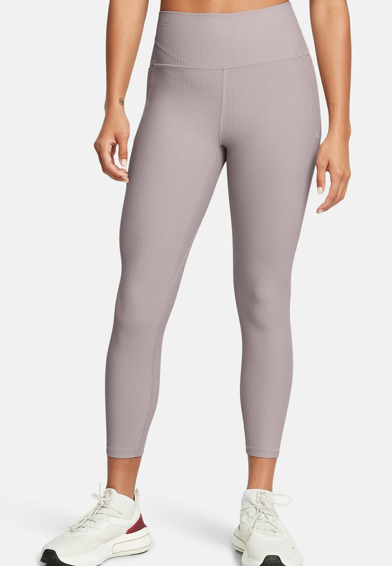 Leggings a vita alta in color lavanda tenue, con una trama a coste e una superficie liscia. Presentano una vestibilità slim e tasche laterali, abbinati a sneakers bianche.