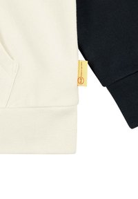 Tweekleurige sweatshirt met een crèmekleurige voorkant en marineblauwe mouwen. Zacht katoen met ribgebreide manchetten en een gele merklabel.