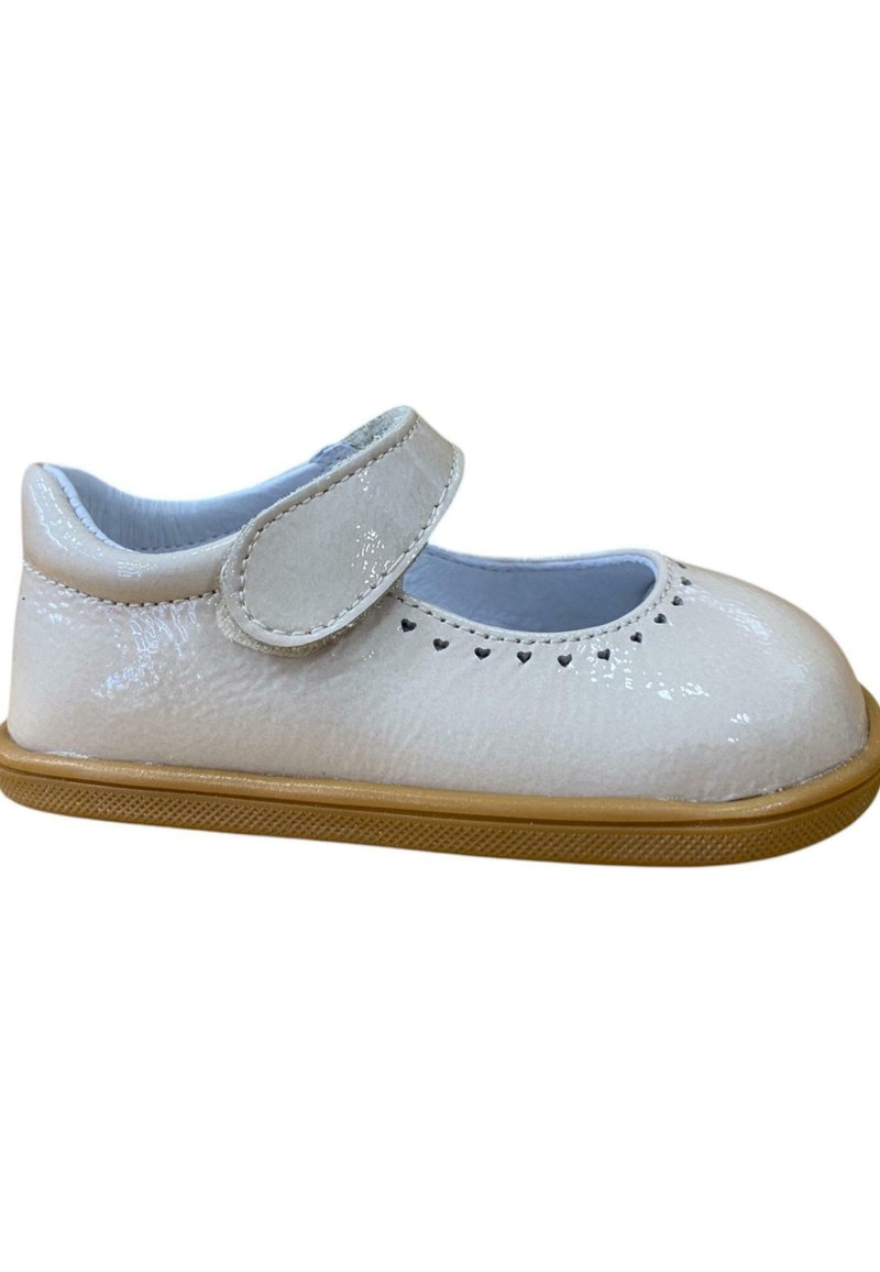 Zapato Mary Jane de charol blanco con punta redonda, correa de velcro y pequeños cortes en forma de corazón a lo largo del borde. Suela de goma de color marrón.