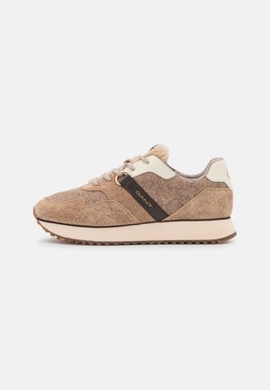 Zapatilla de ante marrón y lana con suela beige, detalles en crema, cordones estampados y una tira con logo negro en el lateral.