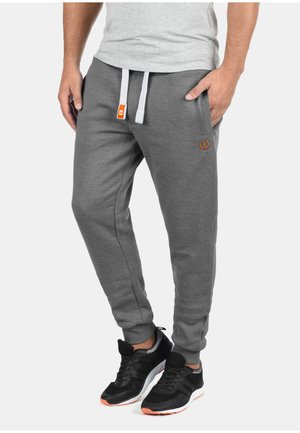 Gray sweatpants made of soft fabric, featuring elastic cuffs, a drawstring waist with white and orange accents, and side pockets.