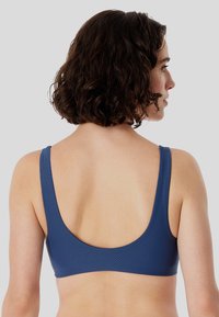 Sujetador deportivo texturizado azul con espalda en forma de scoop y tirantes anchos, diseñado para comodidad y soporte. Sin herrajes o acentos visibles.