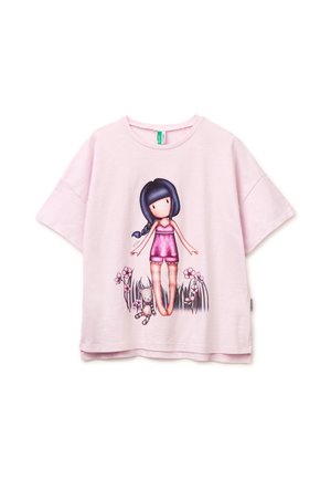 Chemise rose clair à manches courtes avec une illustration d'une fille portant une tenue rose, aux longs cheveux foncés, debout parmi l'herbe, les fleurs et un animal en peluche.