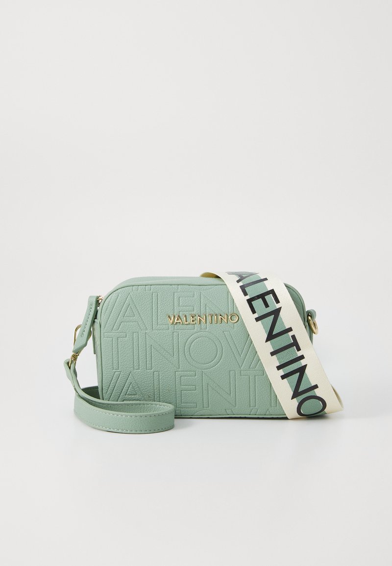 Πράσινη υφασμάτινη δερμάτινη τσάντα crossbody με λεπτομέρειες χρυσού λογότυπου και φαρδιά λωρίδα με μαύρα γράμματα. Συμπαγές ορθογώνιο σχήμα.