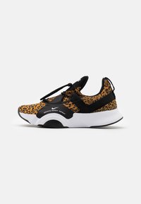 Zapatilla deportiva con estampado de leopardo que presenta detalles en negro, una suela acolchada y un sistema de cordones con ajuste ajustable.