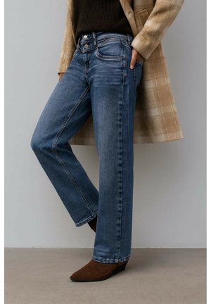 Jasnoniebieskie jeansy dżinsowe o prostych nogawkach, z pięcioma kieszeniami i zamkiem błyskawicznym, w zestawie z brązowymi botkami za kostkę i kremowym płaszczem w kratę.