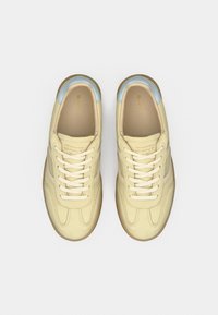 Ανοιχτό κίτρινα αθλητικά παπούτσια με λείο δερμάτινο φινίρισμα, υφασμάτινα στοιχεία, ταμπά κορδόνια και γαλάζιο επενδεδυμένο κολάρο. Λαστιχένια επίπεδη σόλα.