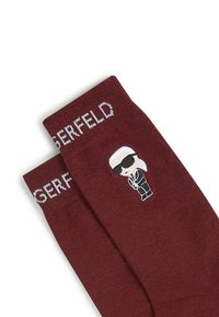 Calze bordeaux con testo ricamato bianco "GERFELD" e un personaggio dei cartoni animati con occhiali da sole e abbigliamento nero sul lato.