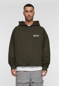 Hooded sweatshirt in dark olive green, made of soft material, features a front pouch pocket and white printed text on the chest.