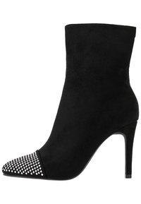 Černá semišová kotníková bota s špičatou špičkou, zdobená stříbrnými nýty na špičce a elegantním vysokým jehlovým podpatkem.