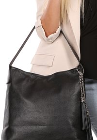 Zwarte leren tote bag met een textuurafwerking, lange schouderriem en een kettingaccent met een kwastje. Glad, ruim ontwerp.