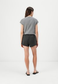 Gray cap-sleeve top with a textured pattern paired with black shorts and black sandals, viewed from the back on a white background.