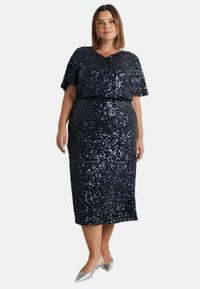 Plus-size šaty z námořnických flitrů, s výstřihem do V a krátkými volánovými rukávy, s přiléhavým střihem a sukní po kolena.