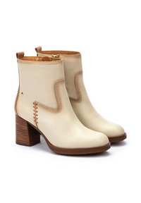 Cream leather ankle boots with a curved seam design, side stitching accents, and a chunky wooden heel. Zipper closure at the back.