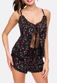 Ensemble de pyjama noir avec imprimé cerises rouges, avec des bordures en dentelle et des bretelles spaghetti réglables. Comprend un haut sans manches et un short assorti.