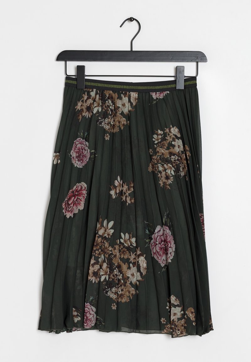 Jupe plissée vert foncé avec des motifs floraux beige et rose, suspendue sur un cintre pince noir sur fond blanc.