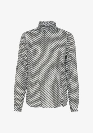Blouse à manches longues avec un col smocké haut, présentant un motif géométrique noir et blanc en formes de diamant et des poignets à boutons.
