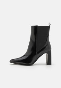 Sorte ankelstøvler lavet af glat materiale, med spids tå, elastiske sider og en bred hæl. Minimalistisk design med en løftestrop.
