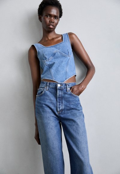 Denim crop top with square neckline and visible seams paired with high-waisted, wide-leg jeans in medium blue denim. Smooth texture.
