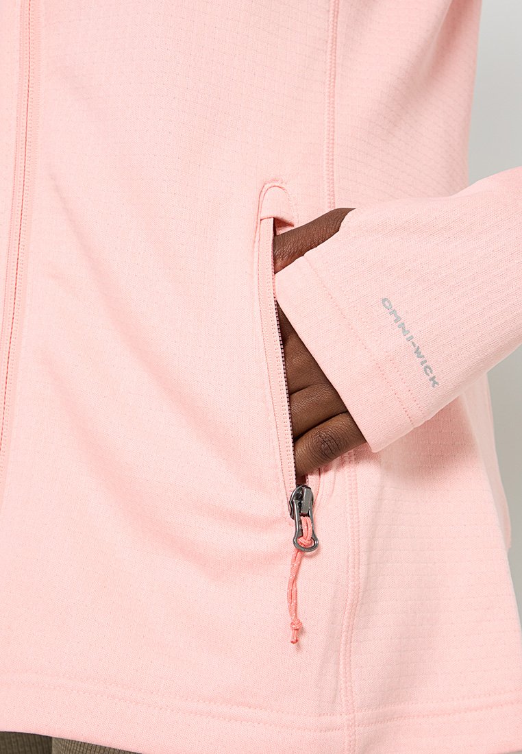 Chaqueta de forro polar de color rosa claro con bolsillos con cremallera, puños de punto acanalado y tejido texturizado. Presenta el logo "OMNI-WICK" en la manga.