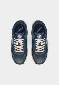 Ζεύγος ναυτικό μπλε αθλητικά παπούτσια Coach με λευκά κορδόνια και κρεμ χρωματιστές σόλες, απεικονιζόμενα από πάνω πάνω σε απλό φόντο.