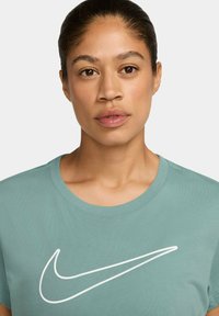 T-shirt Nike in cotone turchese chiaro, con un grande logo swoosh bianco sul petto. Design classico con collo a giro e maniche corte.