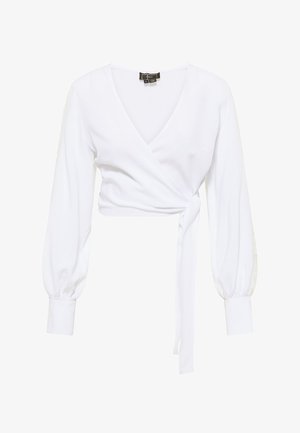 Witte wikkelblouse met een diepe V-hals, lange puffmouwen, een getailleerde strik in de taille en kanten accenten op de mouwen. Zachte, gladde stoftextuur.